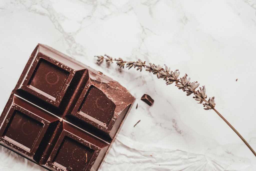 Artistic shot of dark chocolate and lavender on a marble background, emphasizing luxury and gourmet appeal.