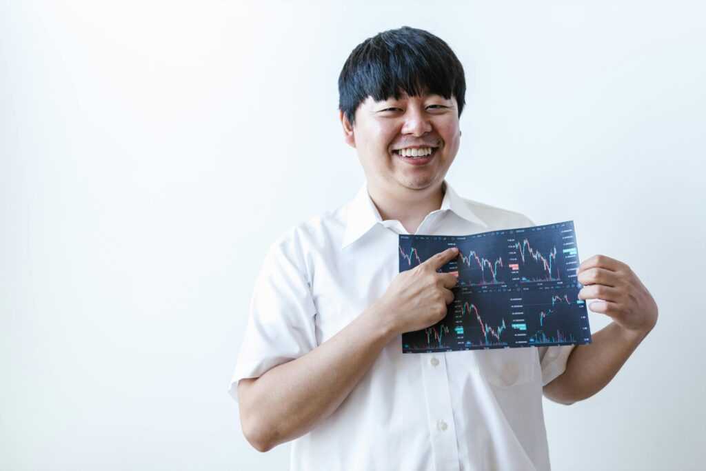 Smiling man presenting cryptocurrency investment chart indoors.